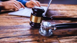 Judge's gavel and medical stethoscope on wooden desk surface representing medical malpractice legal proceedings
