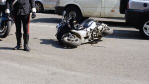 A police officer standing near a crashed motorcycle on a road, with another bike and vehicles in the background, at 11:27 PM CEST on September 16, 2025.