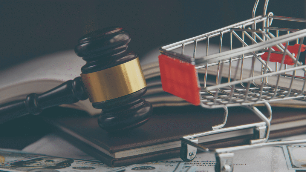 A gavel on books with a shopping cart and money, symbolizing legal and financial aspects of a case.