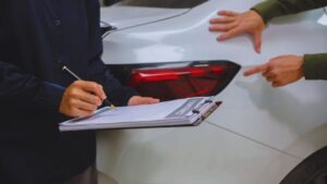 Insurance adjuster documenting damaged white car after accident; guide for denied car accident claims in Alberta 2026.
