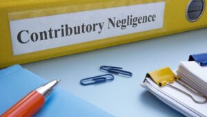 Yellow binder labeled "Contributory Negligence" on desk with paperclips, pen, and documents, legal concept file.
