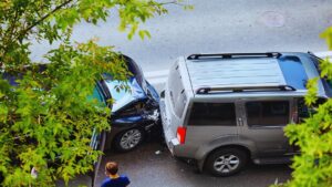Aerial view of a two-car automobile accident on a city street, with a bystander on the phone at the scene.