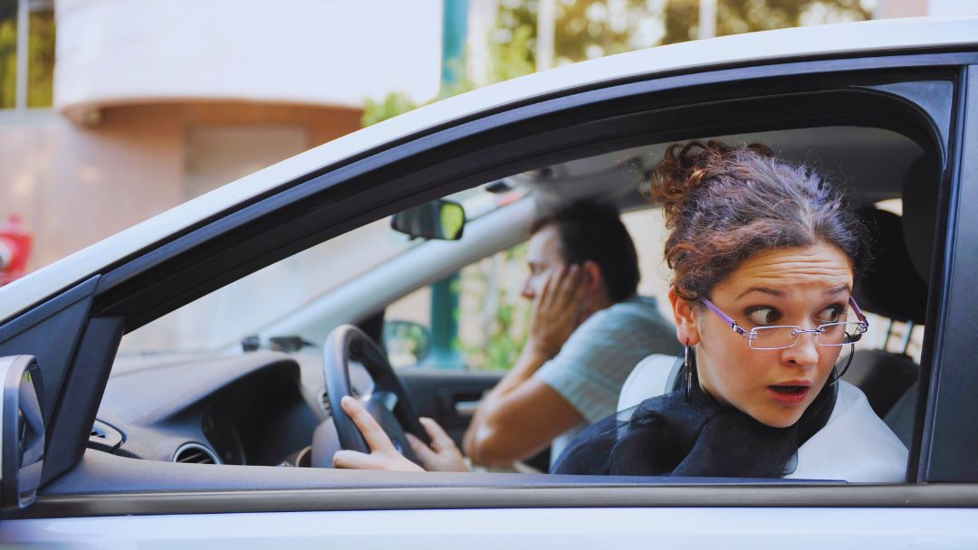 Startled driver leaning out of car window after a parking lot accident, raising the question of who is at fault under Alberta law.