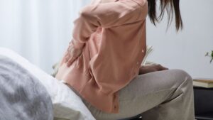 Woman holding her lower back in pain, representing soft tissue injuries subject to Alberta's Minor Injury Regulation compensation cap.