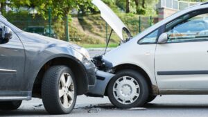 T-Bone Accident Who Is At Fault Alberta Law Explained. Close-up of a t-bone collision between a dark SUV and a silver car with the hood open, front-end damage, and debris on the road.